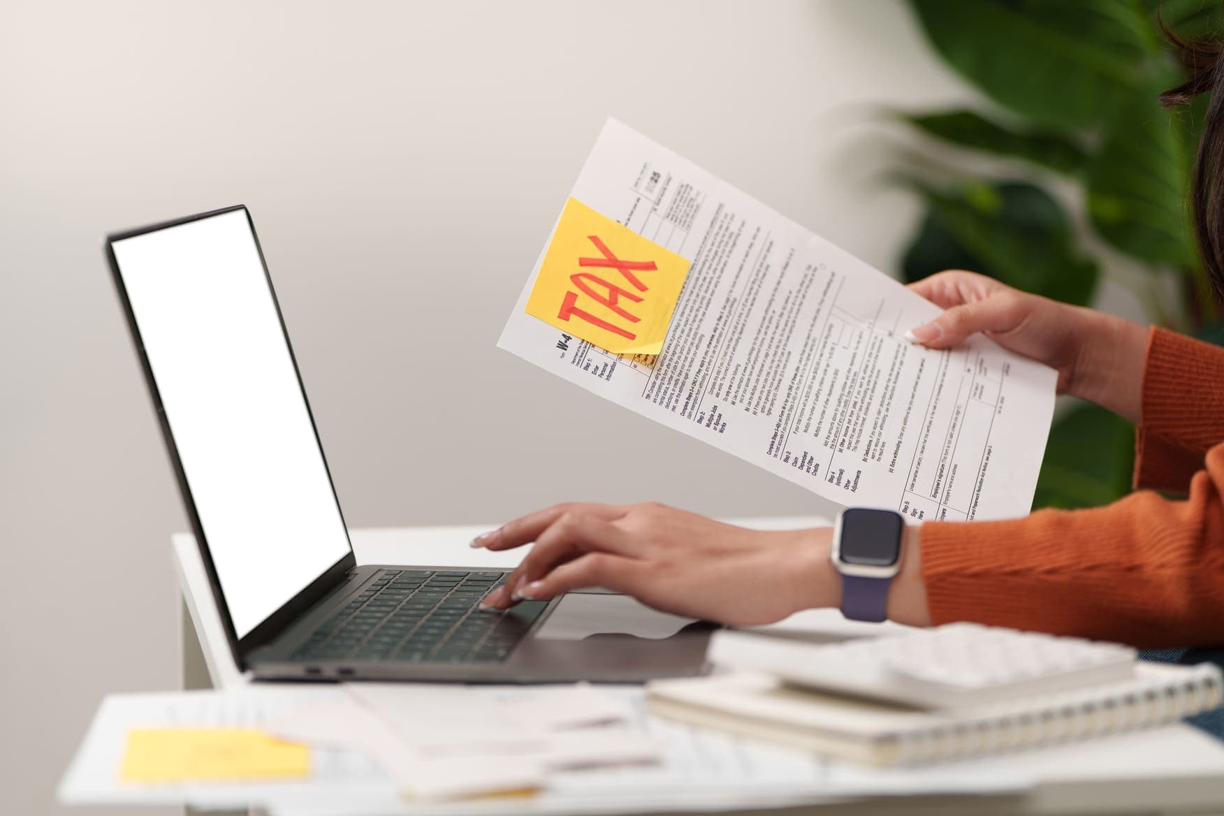 A person reviewing a tax form next to a laptop